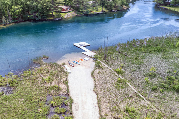 Living room with wood-paneled walls, large leather sectional sofa, glass coffee table, and dining area.