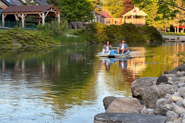 A couple enjoys a pedal boat ride in The picturesque backyard canal at CozyCotts Villa, alongside Lake Simcoe, Ontario, the closest lake to Toronto.