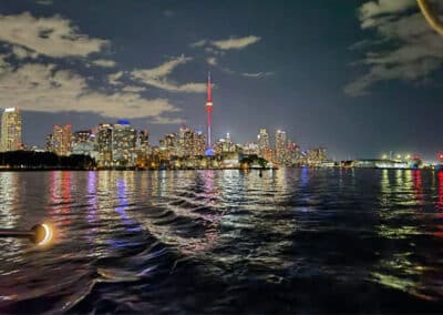 夜晚城市天际线灯光倒映水面，中央高塔突出，天空有稀疏云朵。